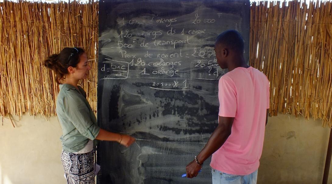 A Projects Abroad volunteer speaks to a local at her placement in Senegal. A Teaching volunteer in Senegal helps a local boy during a lesson.
